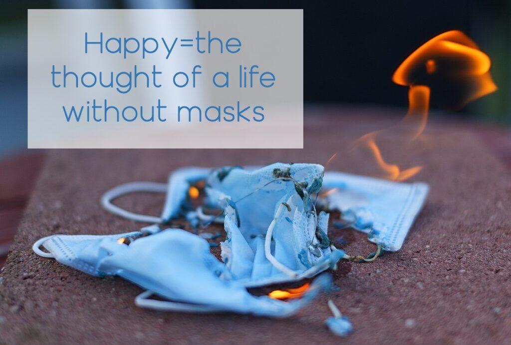 a blue mask on the concrete in flames with "Happy=the thought of a life without masks"
